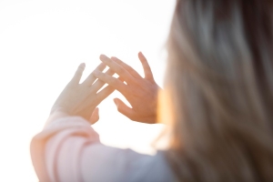 Frau hält ihre Hände mit brüchigen Fingernägeln gegen die Sonne