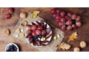 Direkte Quellen von Resveratrol, Weintrauben und Nüsse, sind dekorativ auf einem herbstlich gedeckten Tisch angeordnet.