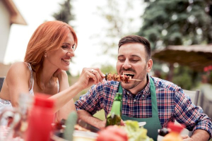 Mann isst Spieß mit Gemüse und rotem Fleisch