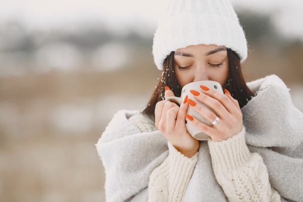 Warm bekleidete Frau im Winter trinkt zum Wohle von Darm und Immunsystem