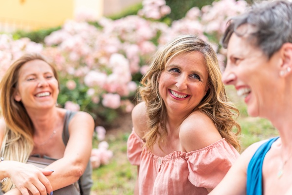 Lachende Frauen ohne Frühjahrsmüdigkeit sitzen im Freien