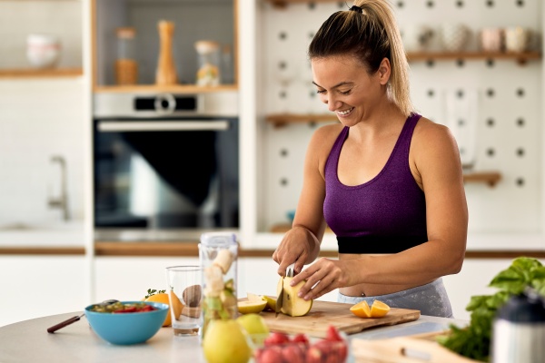 Frau schneidet Obst, um gesund abzunehmen