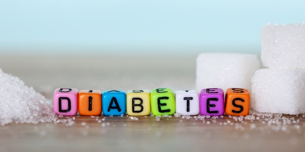 Mit farbigen Perlen gelegt das Wort Diabetes zwischen Zuckerwürfeln, um auf die weitverbreitete Zuckerkrankheit aufmerksam zu machen.