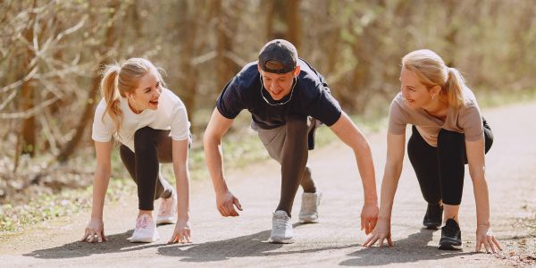 Drei Menschen in Startposition, um Laufen als Sport für Anfänger zu beginnen