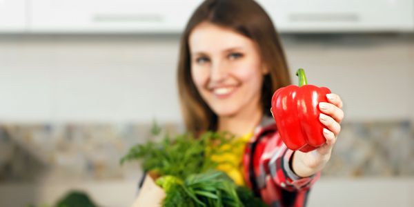 Frau hält Paprika als ein Lebensmittel mit Antioxidantien in die Kamera
