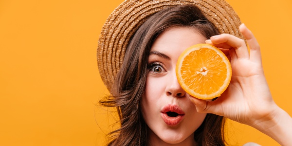 Frau mit einer Scheibe Orange als Symbol für Lebensmittel mit Vitamin C