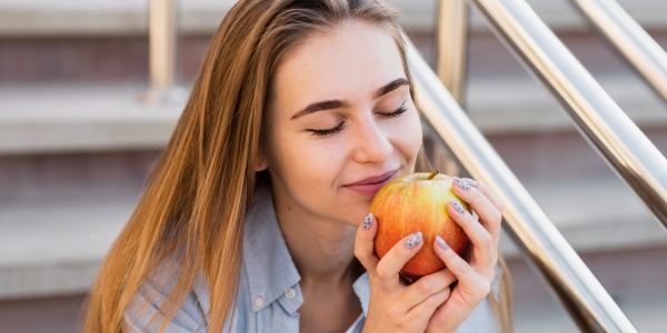 Frau riecht genussvoll an einem Apfel mit Apfelpektin
