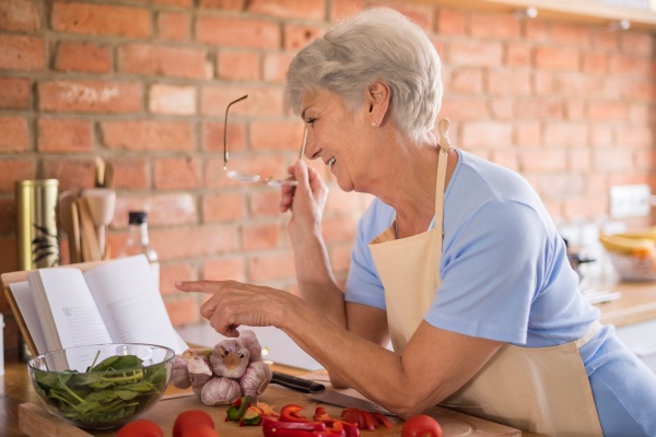 Frau vor einem Kochbuch sucht Ernährung bei Osteoporose