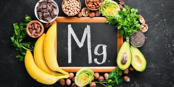 Lebensmittel mit Magnesium rund um eine Tafel mit dem Mengenelement Mg