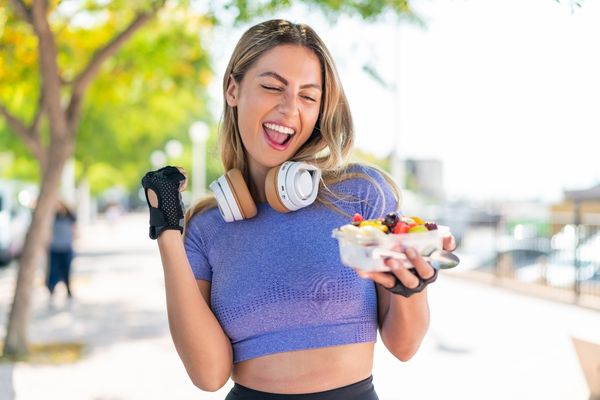 Frau belohnt sich nach dem Sport mit köstlichem Obstsalat