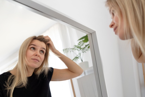 Frau betrachtet sich im Spiegel