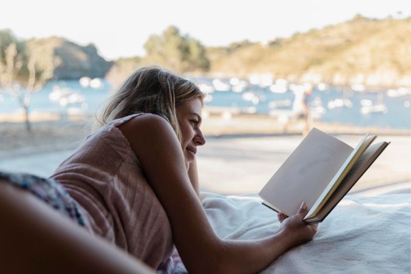 Liegende Frau liest ein Buch zur Entspannung, um besser zu schlafen bei Hitze