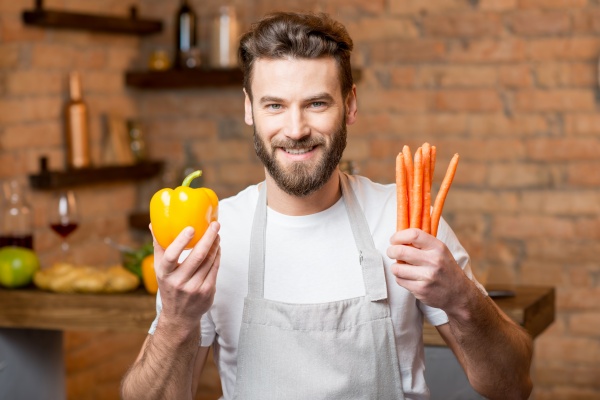 Mann mit Karotten und Paprika für die Fruchtbarkeit